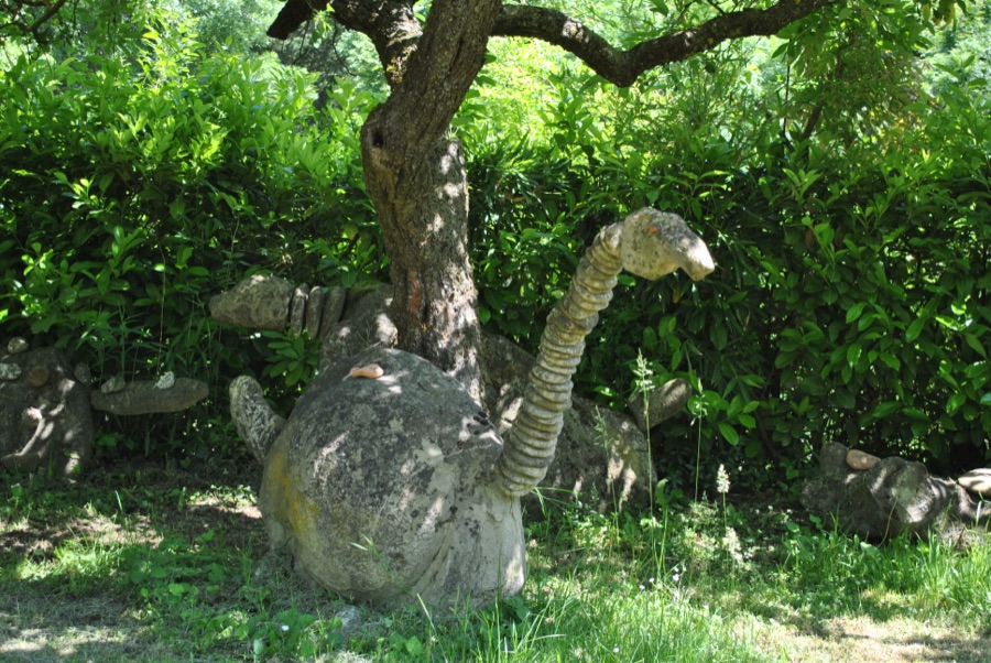 Apatosauro di sasso con il collo a ciottoli che si avvolge attorno al tronco di un albero