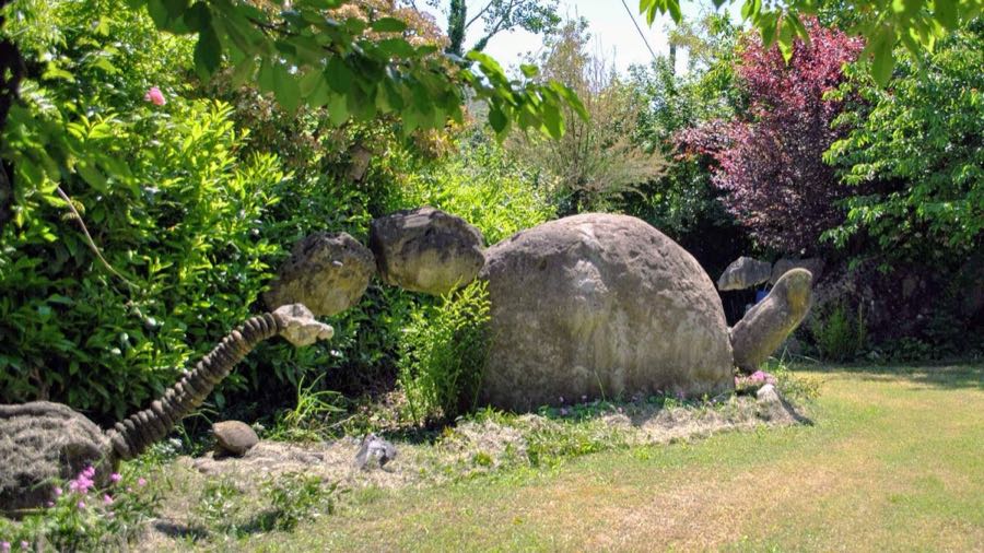 Un dinosauro di pietra immerso nel verde del giardino di Codrignano