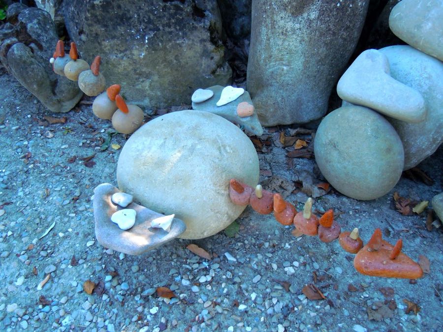 Piccole sculture a forma di pulcino con becco arancione, in fila su un masso tondo