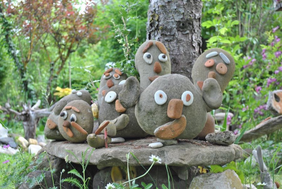 Un gruppo di piccole sculture di sasso con facce buffe, sedute su un tavolo di pietra