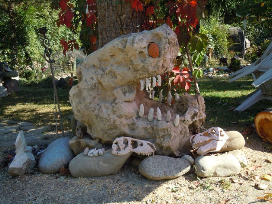 Grande testa di dinosauro scolpita nella pietra, con denti bianchi